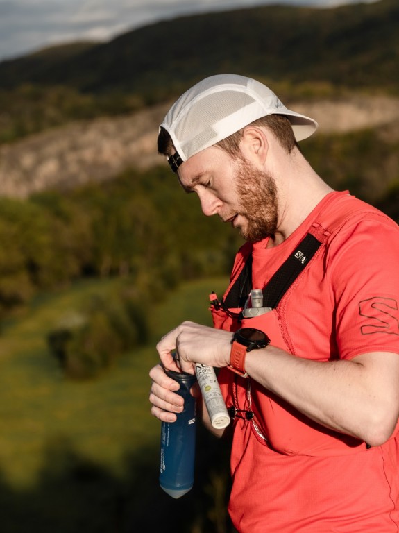 Běžec si připravuje sportovní výživu, aby si doplnil energii