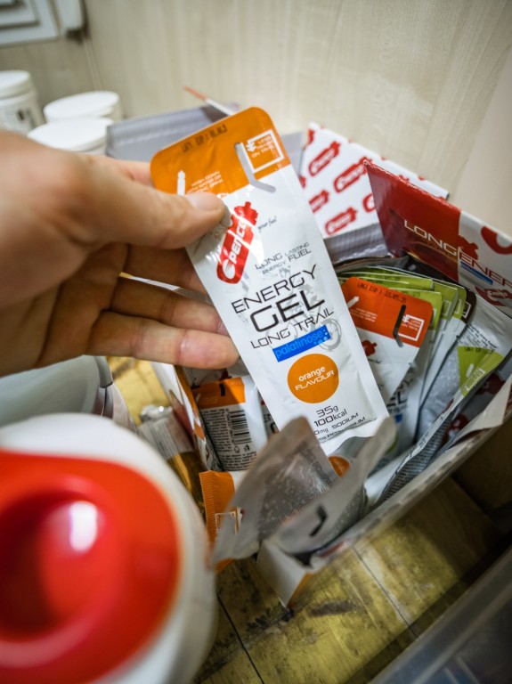 Mužská ruka si z balíčku sportovní výživy Penco vyndává Energy Gel Long Trail.