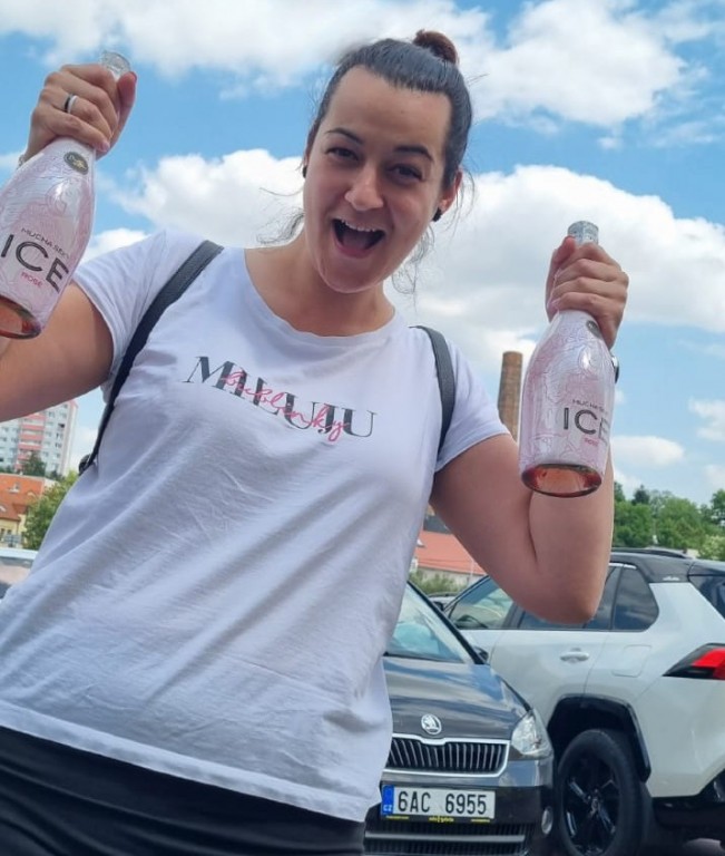 Radana drží v obou rukách sekt a usmívá se.
