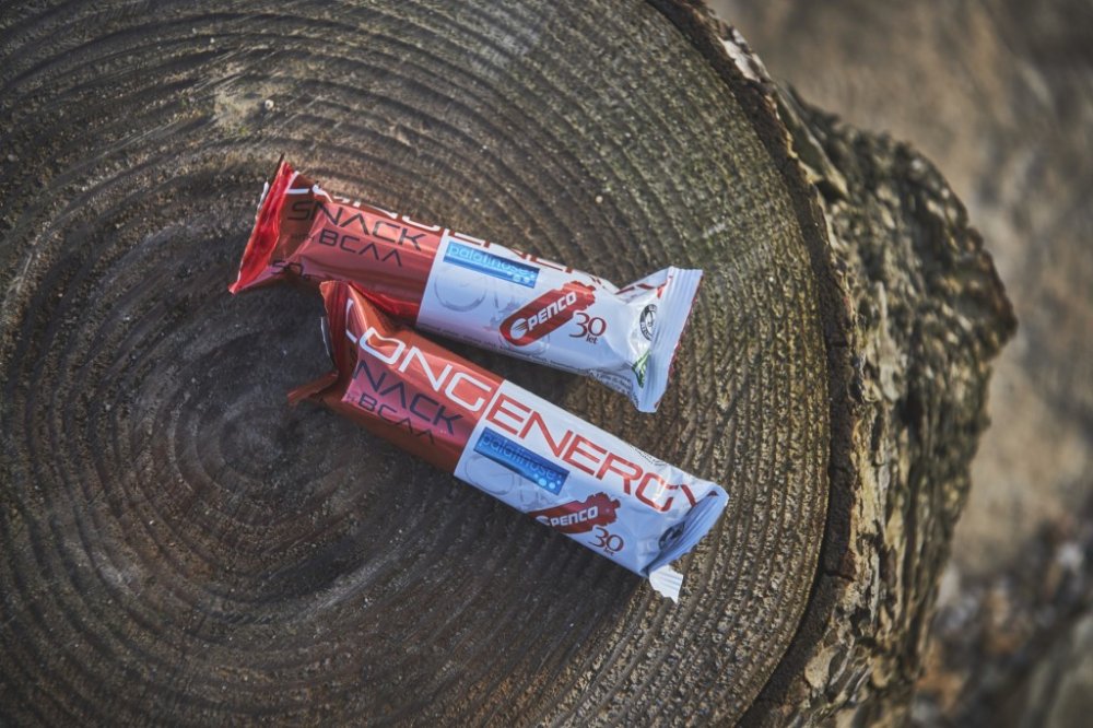 Dvě tyčinky Penco Long Energy Snack leží na pařezu.