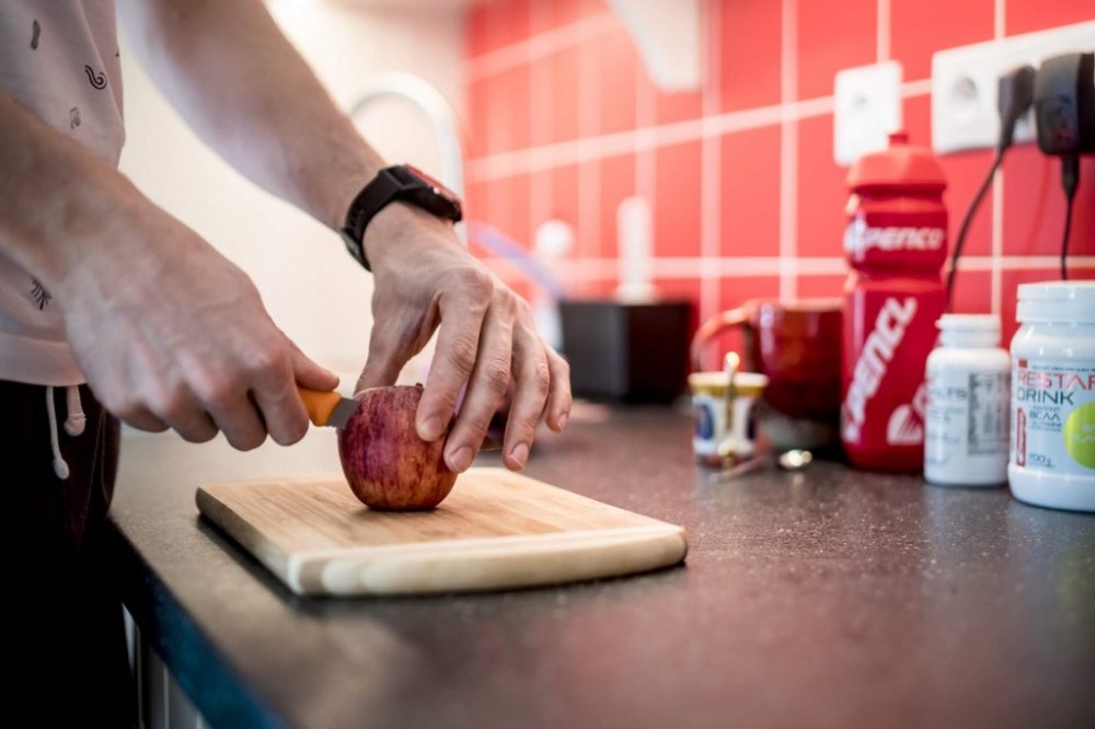 Sportovec si na kuchyňském prkénku krájí jablko