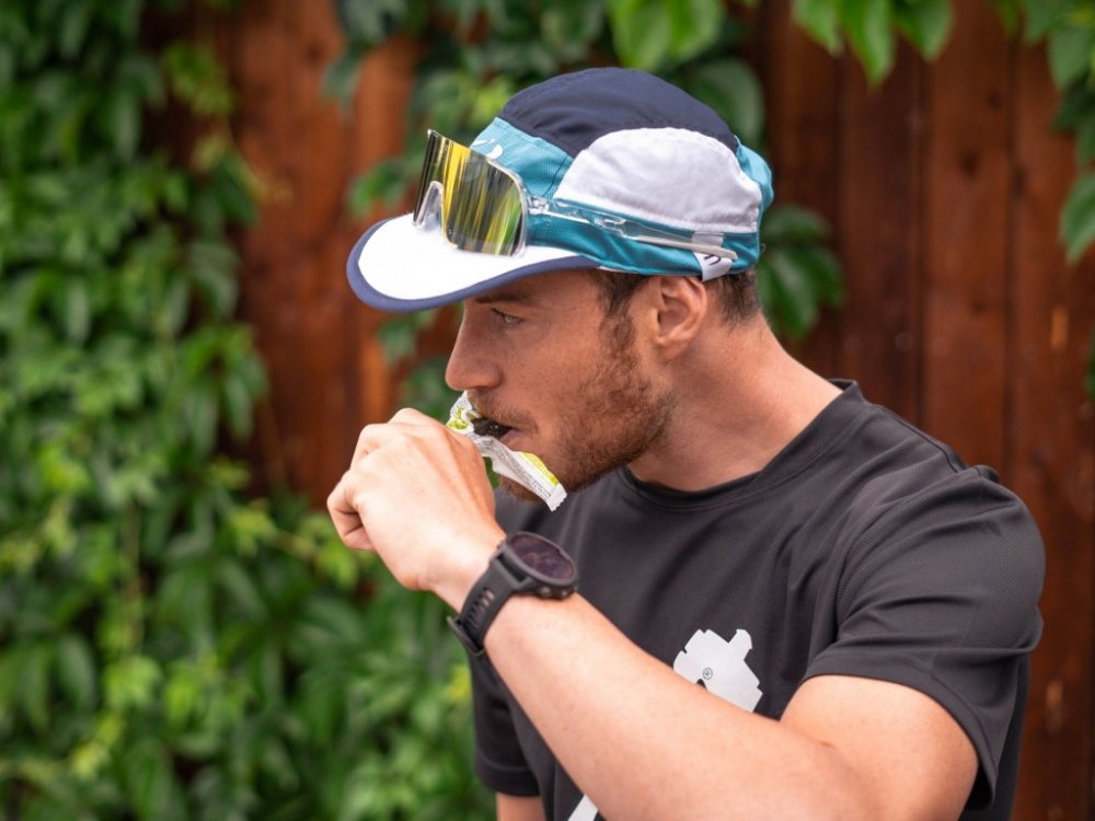 Pavel Wohl v černém tričku Penco kouše do energetické tyčky Penco.